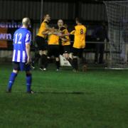 Fakenham Town's players mob Robbie Harris after his late, late equaliser. Picture: TONY MILES