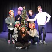 The Cinderella cast gather around the Christmas tree at Sheringham Little Theatre