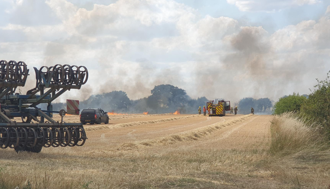 Crews tackle large field blaze as smoke billows near village